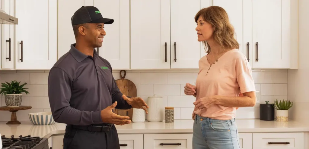 Terminix technician speaking to customer in her kitchen